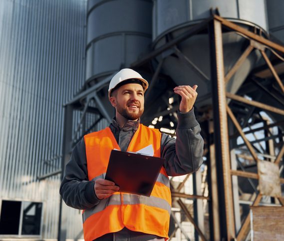 Bauerarbeiter in Uniform ist draußen in der Nähe der Fabrik